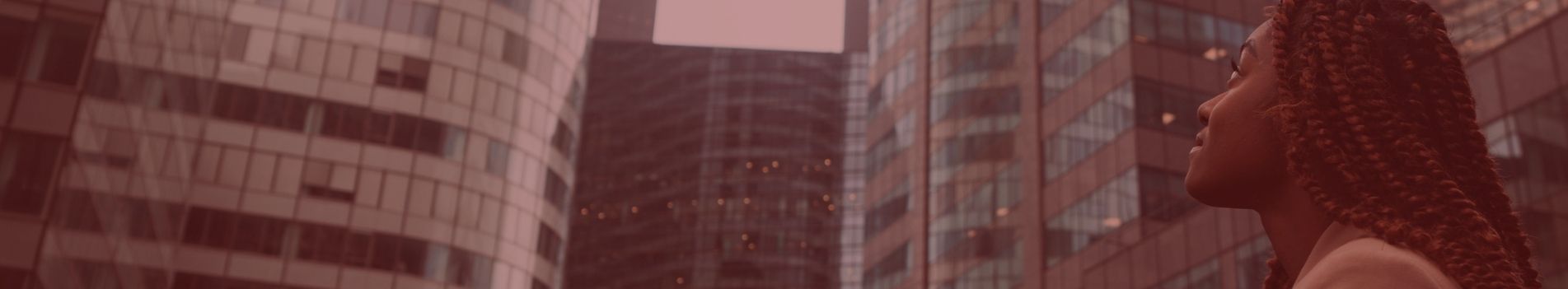 Jeune femme regarde vers le ciel dehors à la Défense devant des grandes immeubles 