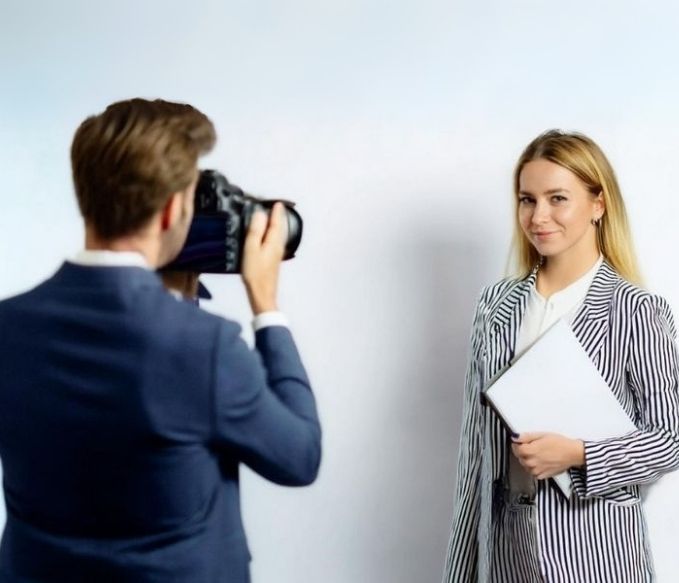 Jeune femme blonde en tenue professionnelle avec un photographe brun de dos